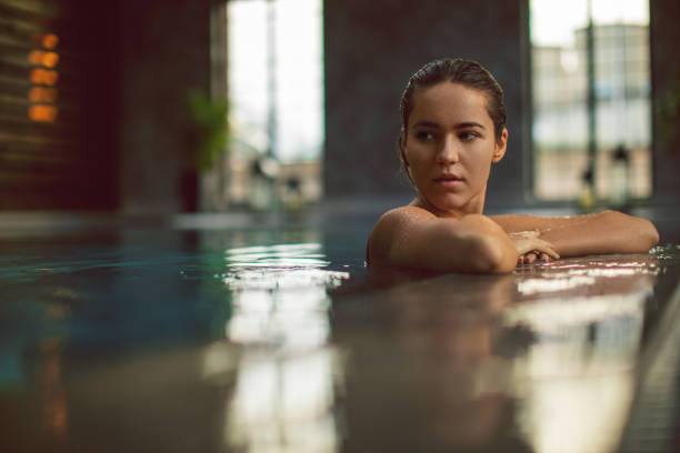 istock Beautiful young woman relaxing on indoors poolside 1200349326