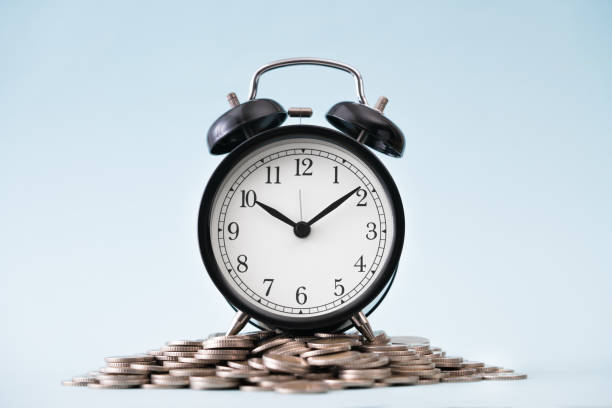coins stack and alarm clock on blue background - stock market data insurance savings finance imagens e fotografias de stock