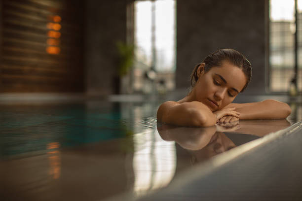 istock Beautiful young woman relaxing on indoors poolside 1200349986