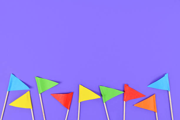istock Colorful small paper flags at bottom on purple background with copy space 1200351939