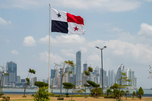 bandera nacional de panamá con horizonte de la ciudad de panamá en el fondo - panama fotografías e imágenes de stock