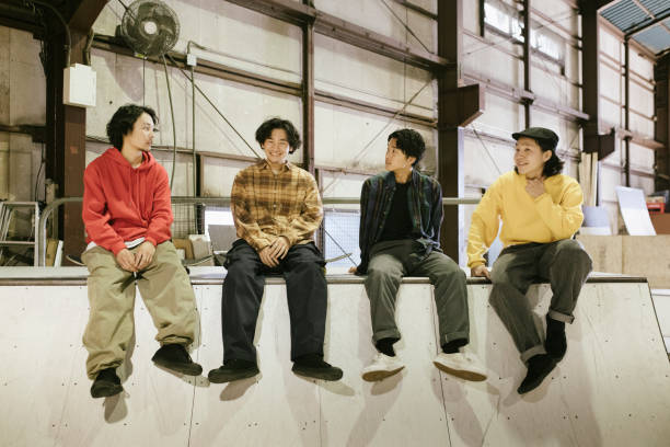 Group of friends sitting on a skateboard ramp, having good time.