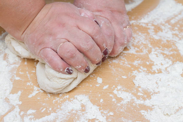istock Kneading dough with flour on a wooden table at home 1200358330