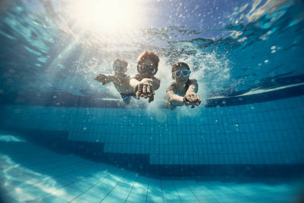 istock Happy kids swimming underwater in pool 1200359689