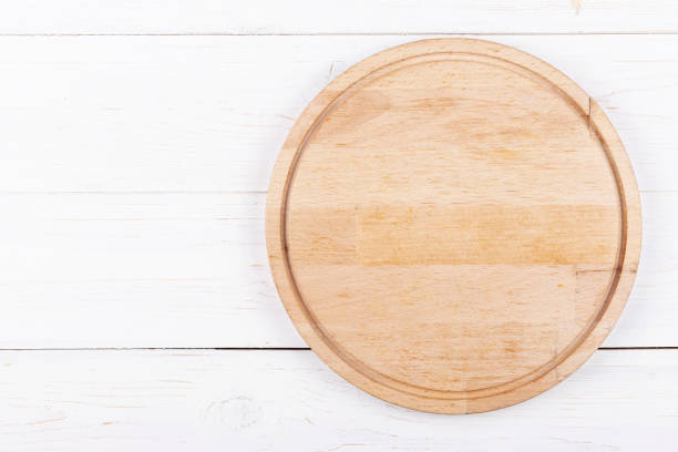 istock Blank round cutting board or pizza board on a light wooden background. 1200362576
