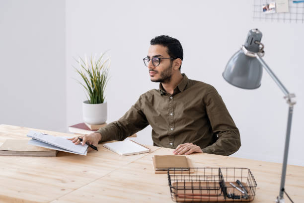 istock Young male student in eyeglasses looking at his notes in notepad 1200365043