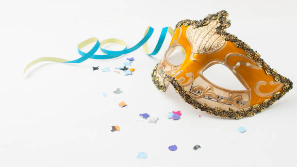 istock Orange venetian carnival mask on white table with some stream and confetti 1200366115