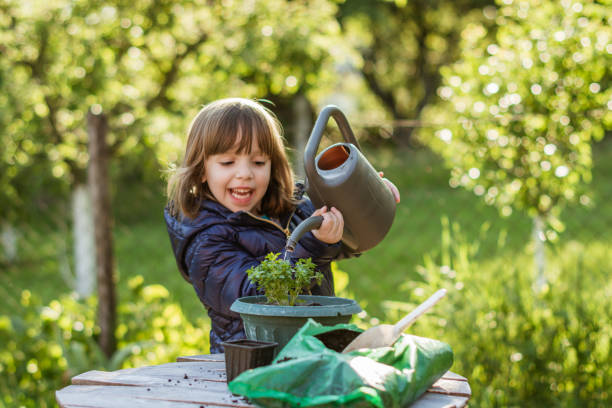 istock Cute little girl watering flowers. 1200368321