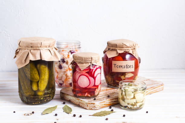Fermented vegetables, pickled, cabbage, cucumbers, radish and garlic in a glass jaron on a light background with copy space. Horizontal orientation