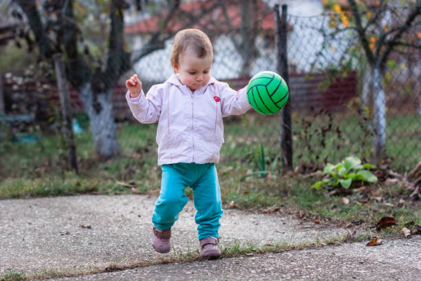 A child playing with a ball in the yard.