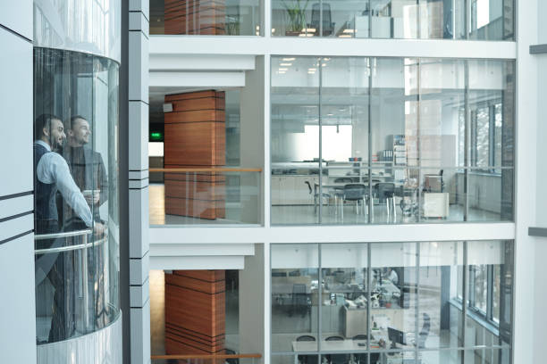 istock Two businessmen moving in elevator inside large contemporary business center 1200370231