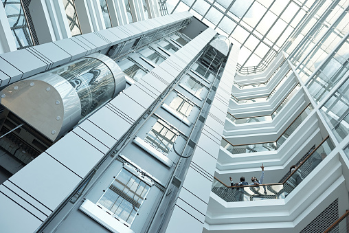 Below view of moving elevator, walls and balconies of contemporary business center that can be used as background