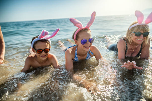 istock Kids and grandmother playing in sea during summer Easter 1200376874
