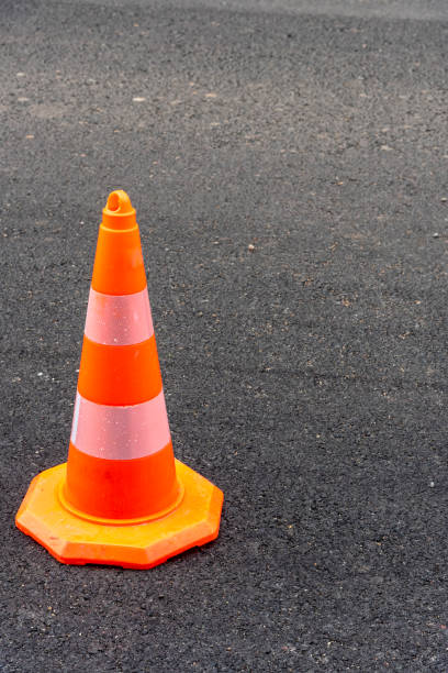 istock Traffic cone, white and orange on gray asphalt, vertical 1200377506