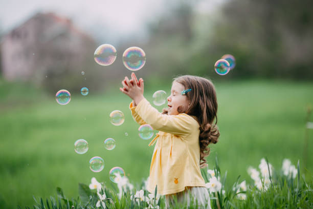 istock Little girl playing with bubbles in the field 1200382064