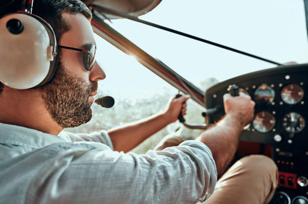 Yong man with beard in an airplane cabin flying a plane Yong man with beard in an airplane cabin flying a plane. Side view. Close up view piloting photos stock pictures, royalty-free photos & images