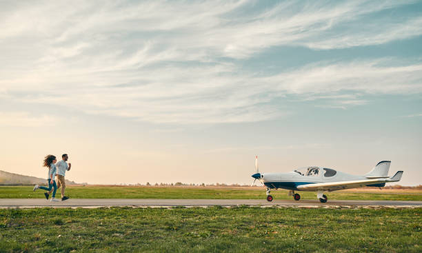 istock Beautiful romantic couple is holding hands, smiling while running on take-off the aircraft 1200382220