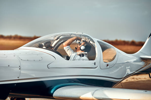 przystojny młody pilot sprawdzający swój ultralekki samolot przed lotem - ultralight zdjęcia i obrazy z banku zdjęć