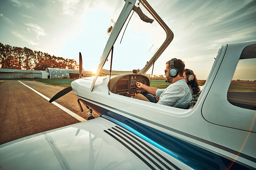Pilot with co-pilot prepare take off in a small aircraft. Side view. Sunset background