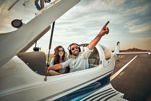 Two pretty beautiful handsome carefree couple having free time in a small plane. Cheerful people looking in the sky at flying bird or plane