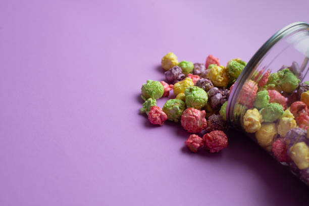 istock Multicolored fruit flavored popcorn in glass cups on pink background. Candy coated popcorn. 1200384666