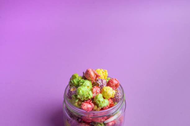 istock Multicolored fruit flavored popcorn in glass cups on pink background. Candy coated popcorn. 1200384671