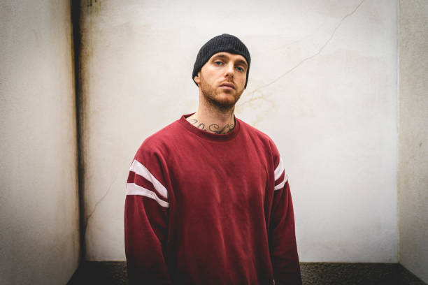 portrait of young rapper posing in front of a white wall in the suburbs