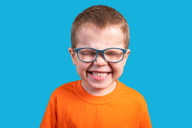The little boy in glasses laughs. Isolated on a blue background. stock photo