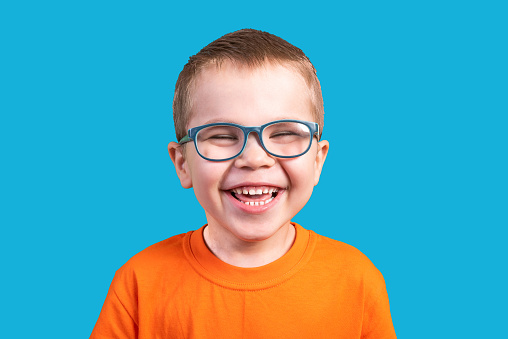The little boy in glasses laughs. Isolated on a blue background.For any purpose.