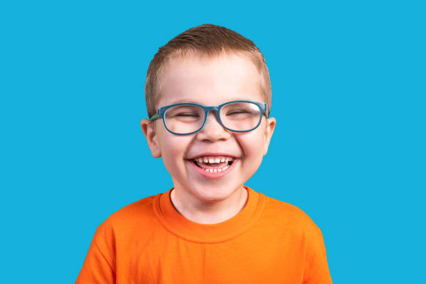The little boy in glasses laughs. Isolated on a blue background. stock photo