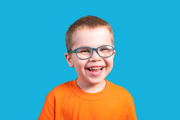 istock The little boy in glasses laughs. Isolated on a blue background. 1200390659