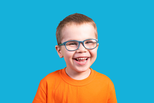 The little boy in glasses laughs. Isolated on a blue background.For any purpose.
