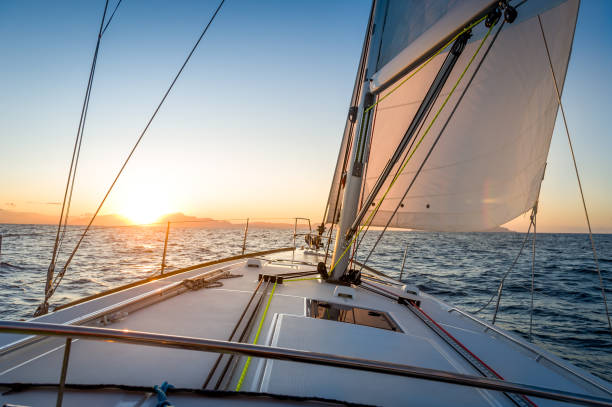 segelyacht navigationg zur sonne aufgehen am horizont - sailboat sunset nautical vessel sun stock-fotos und bilder