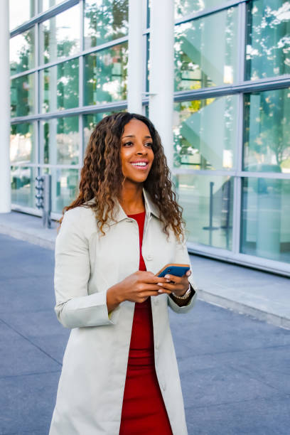 istock Smiling woman walking with phone 1200392055