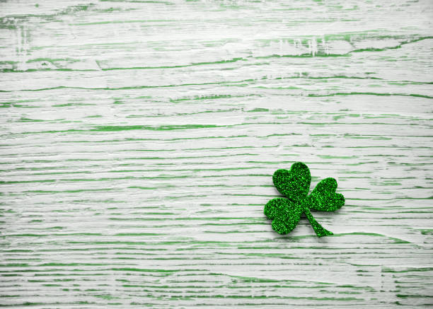 St. Patrick's day. Shiny Shamrock, clover leaf on a light wooden background.
