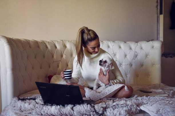 istock Woman using laptop computer sitting on bed at home 1200394525