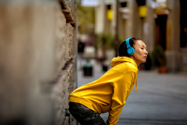 Young beautiful female relaxing after training. Attractive female runner taking break after jogging outdoors. Fit woman during workout in early morning. Portrait of tired fitness young woman catching breathe. Women are tired From jogging on a steep slope fit mujer atleta descansando al aire libre. feliz mujer atlética descansando mientras se apoya en una pared en la ciudad. joven deportista escuchando música mientras se toma un descanso de hacer ejercicio y apoyarse en una pared al aire libre. copiar esp