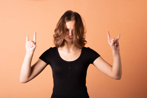istock A girl shows a rocker goat, on a light orange background. 1200401369