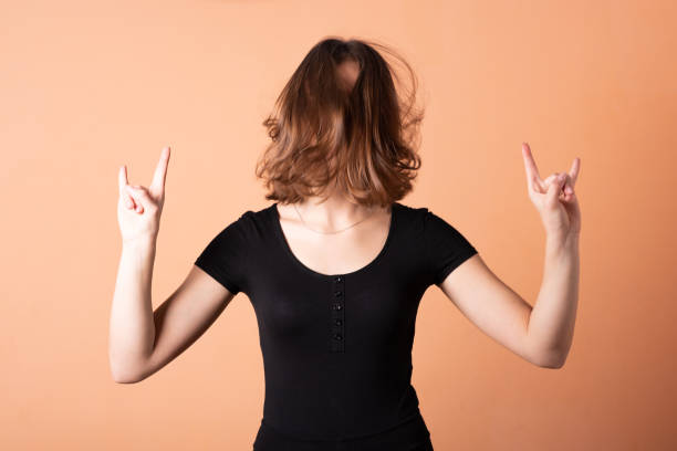 istock A girl shows a rocker goat, on a light orange background. 1200401373