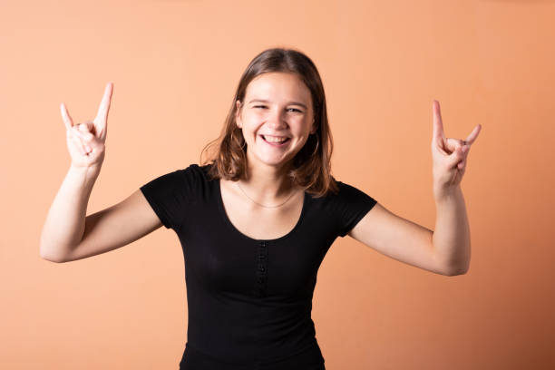 istock A girl shows a rocker goat, on a light orange background. 1200401387