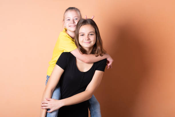 istock Two girls, sisters, on a light orange background. 1200401716