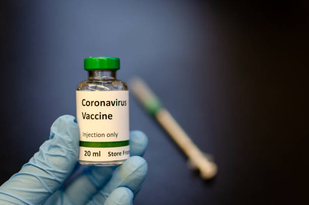 Doctor holding coronavirus vaccine vial with syringe at the background Vial labelled as coronavirus vaccine for photography purpose only. research foundation stock pictures, royalty-free photos & images