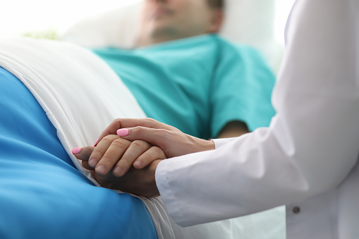 Las manos de la doctora femenina sostienen el brazo masculino en el hospital médico photo