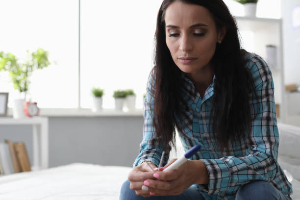 istock Sad mature woman sidin on bed and holds test 1200405374