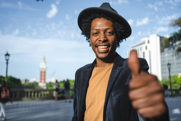 istock Cheerful hipster holding a thumbs up on town square 1200409494