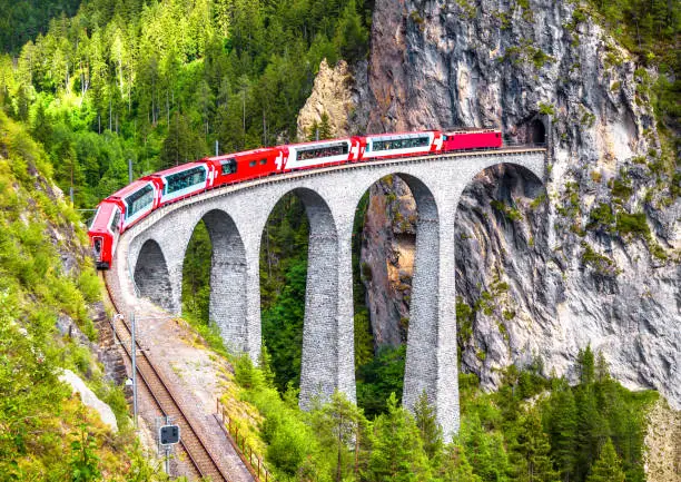 Landwasser Viaduct in Filisur, Switzerland. It is landmark of Swiss Alps. Bernina Express train on railroad bridge in mountains. Aerial scenic view of famous railway. Nice Alpine landscape in summer.