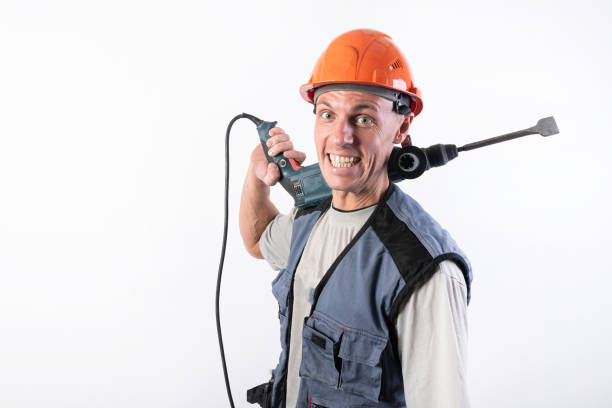 istock A builder with a funny expression, in a helmet, with a drill on his shoulder. 1200411159