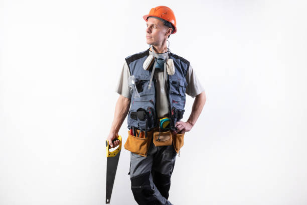 istock The builder in a helmet, and unloading, holds a hacksaw in his hands on a tree. On a light background. 1200413154