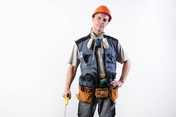 istock The builder in a helmet, and unloading, holds a hacksaw in his hands on a tree. On a light background. 1200413163
