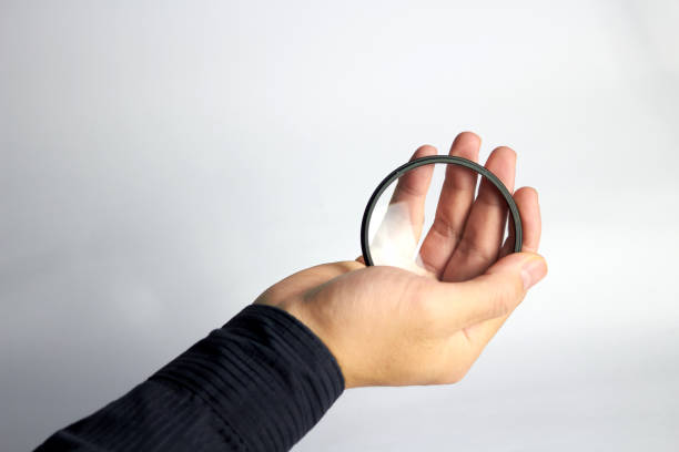 istock Hand holds clear or uv protector lens camera filter on white background 1200416023